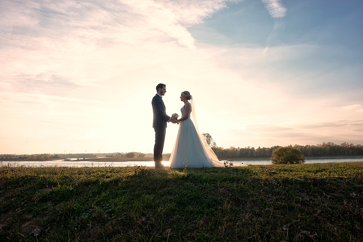Hochzeitsfotografie Brautpaar an einem Damm mit untergehenden Sonne