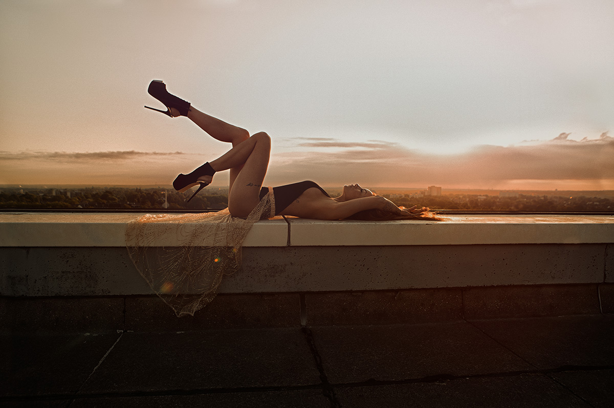 Outdoorfotografie weibliche Person liegt auf einer Mauer bei Sonnenaufgang