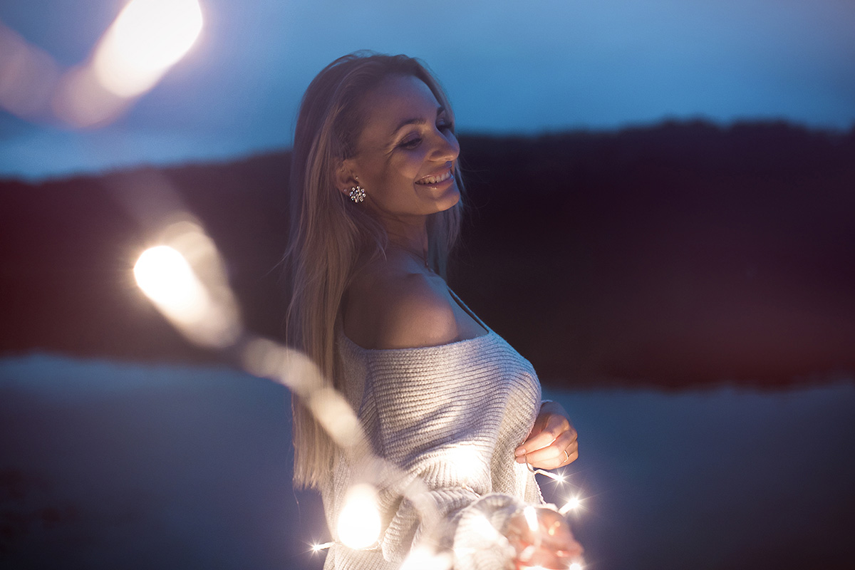 Outdoorfotografie weibliche Person zur blauen Stunde mit einer Lichterkette