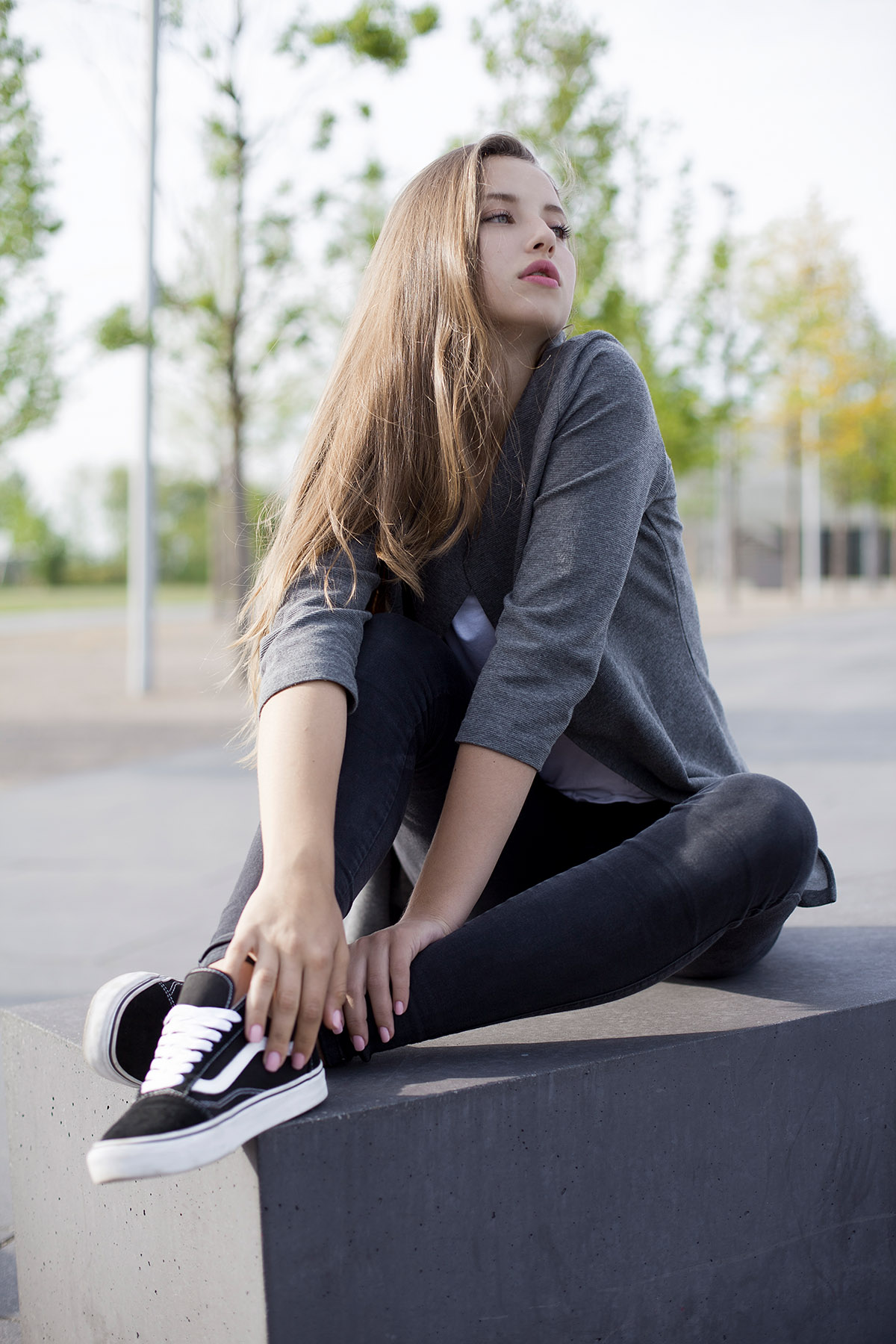 Outdoorfotografie weibliche Person im Aussenbereich, graues Oberteil schwarze Jeans und Vans Schuhe