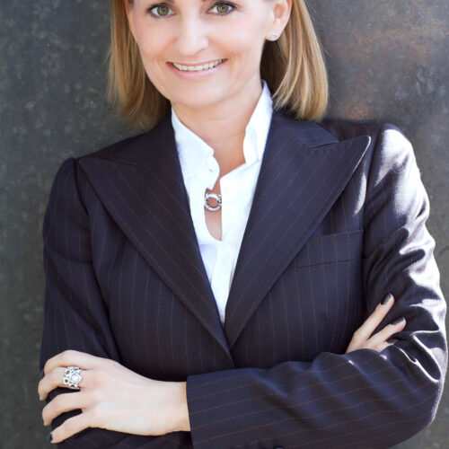 Corporate-Portrait: Managerin im dunklen Blazer vor schwarzem Hintergrund.