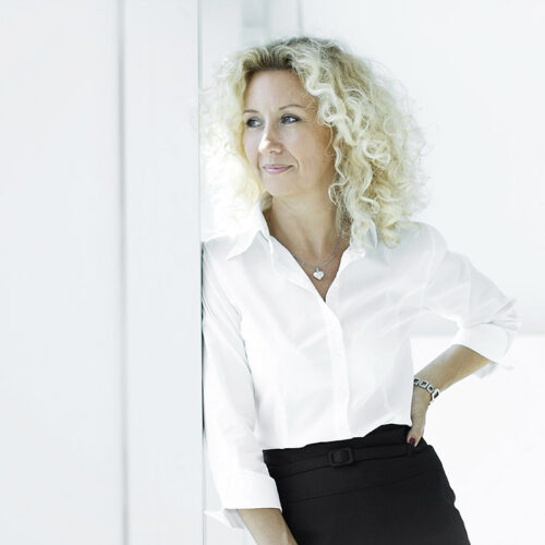 Corporate-Portrait: Geschäftsfrau mit Brille posiert in einem modernen Büro.