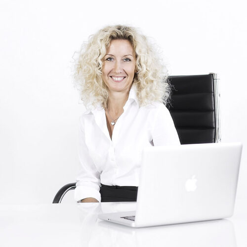 Business-Portrait: Frau arbeitet konzentriert an einem Laptop im Fotostudio.