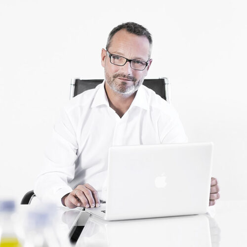 Businessfotografie: Unternehmer am Schreibtisch mit Laptop für Corporate-Broschüre.