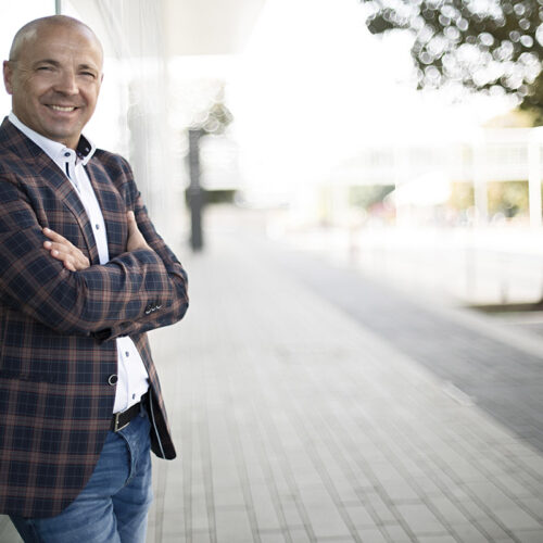 Business-Portrait Outdoor: Mann im karierten Sakko vor moderner urbaner Architektur.
