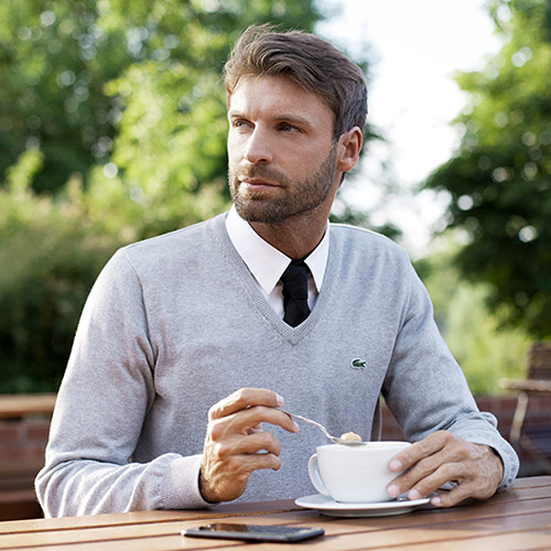 Werbefotografie männliche Person im Lacoste Oberteil in einem Cafe in der Natur