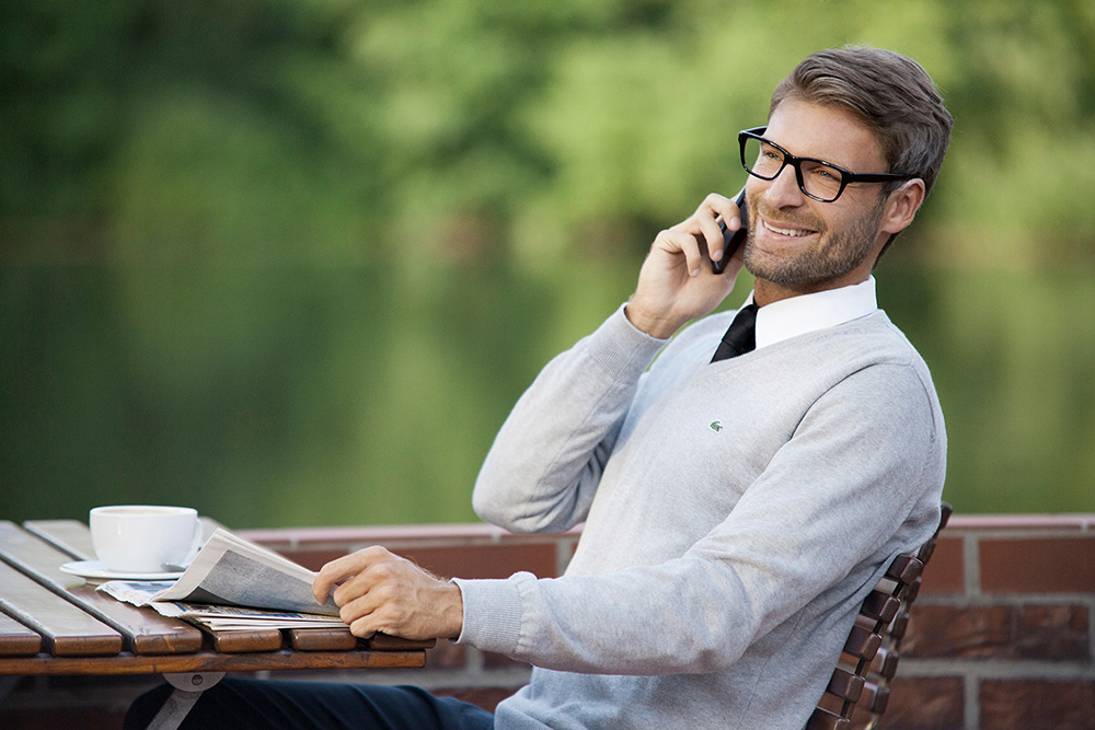 Werbefotografie männliche Person im Lacoste Oberteil beim Telefonieren in einem Cafe in der Natur