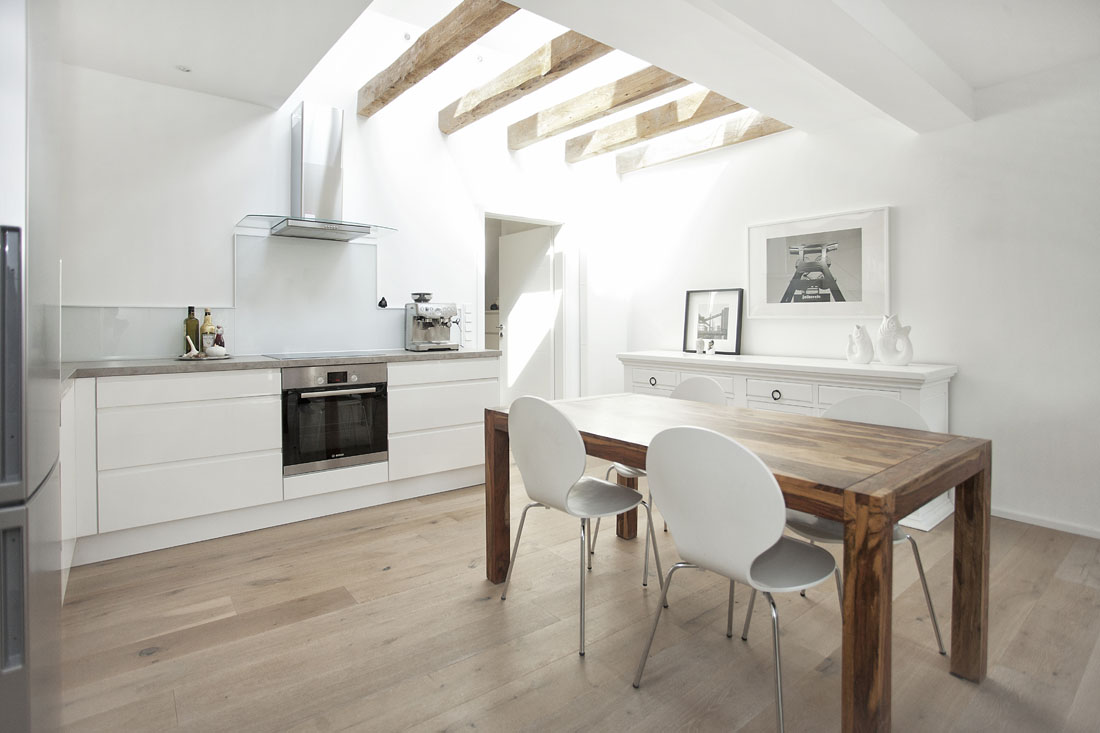 Architekturfotografie weisse Küche mit Holzboden und weißen Möbeln.