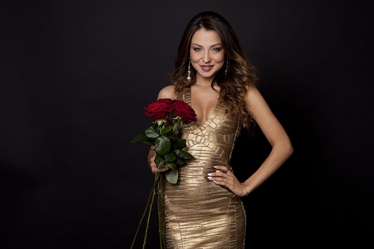Studiofotografie weibliche Person mit langen braunen Haaren im goldneen Kleid mit roten Rosen