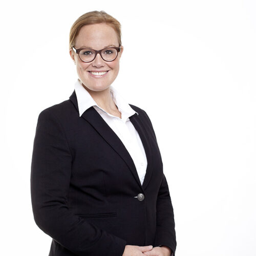 Corporate-Portrait: Lächelnde Geschäftsfrau im schwarzen Blazer vor weißem Hintergrund.