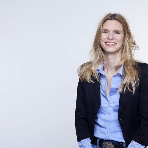 Corporate-Portrait: Selbstbewusste Geschäftsfrau im Business-Outfit vor hellem Hintergrund.