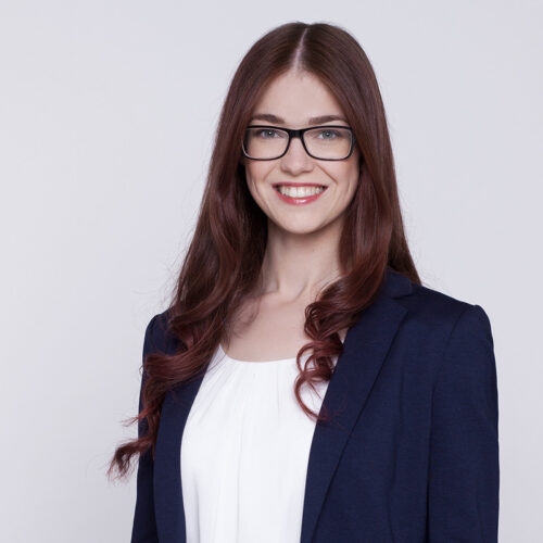 Business-Porträt: Freundlich lächelnde Geschäftsfrau mit Brille und blauem Blazer.